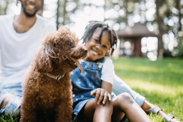 Family and a poodle puppy at a park.